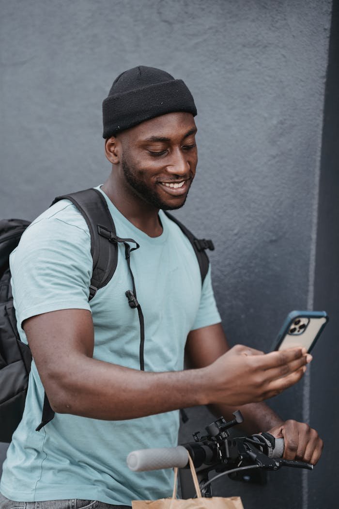 Cheerful delivery person checking smartphone while making a delivery outdoors.