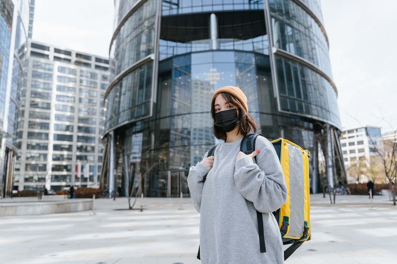 Young courier with thermal bag in urban setting, ready for delivery.
